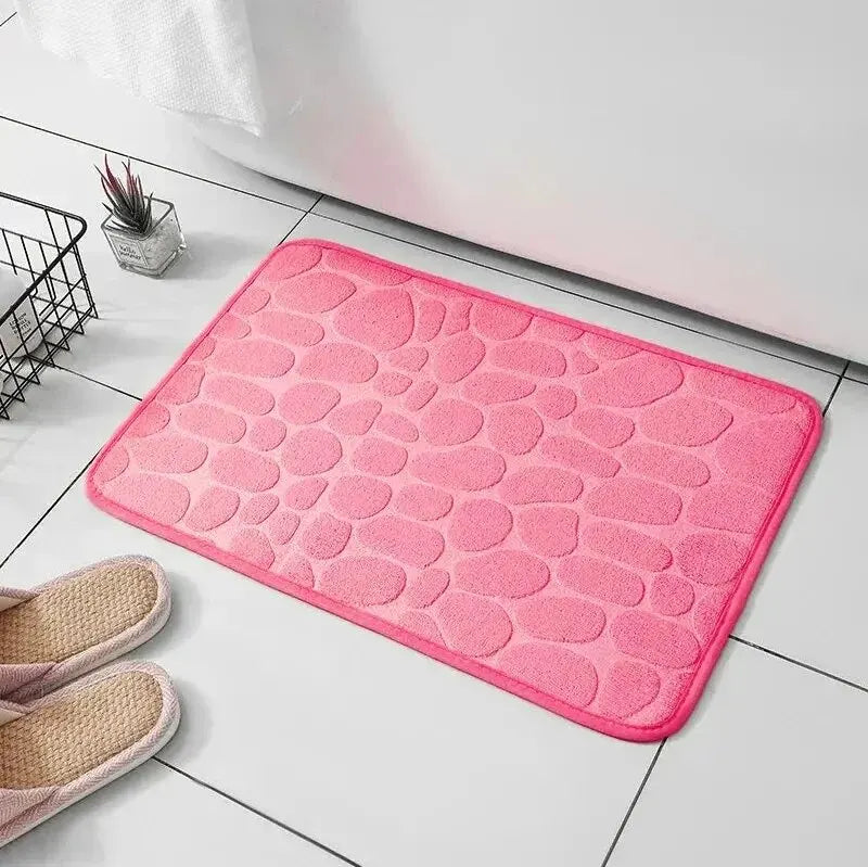 GLOBGRIP pink anti slip pebble floor mat placed on white tiled floor near slippers