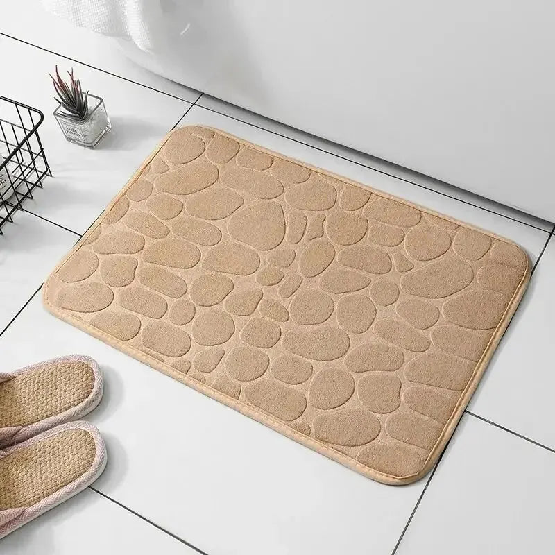GLOBGRIP beige anti slip pebble floor mat placed on white tiled floor near slippers