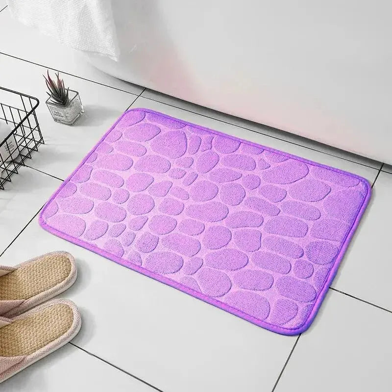 GLOBGRIP purple anti slip pebble floor mat placed on tiled bathroom floor with slippers nearby