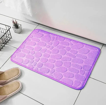 GLOBGRIP purple anti slip pebble floor mat placed on tiled bathroom floor with slippers nearby