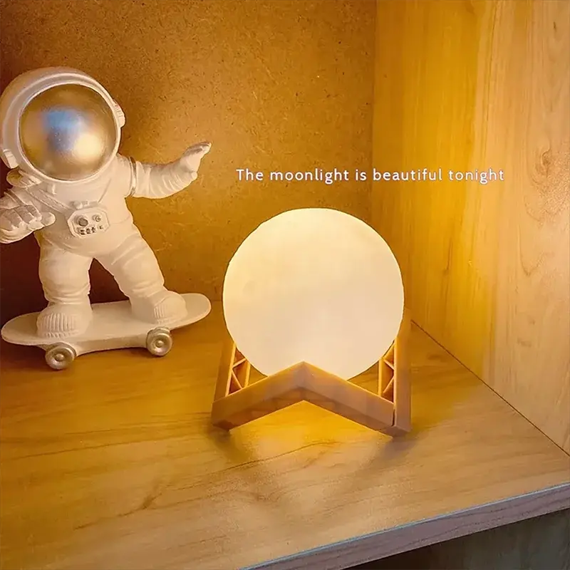 GLOBGRIP Book Light LED Moon Galaxy Night Light glowing warmly on wooden stand with astronaut decor