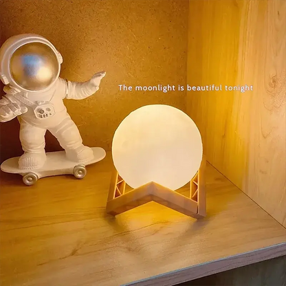 GLOBGRIP Book Light LED Moon Galaxy Night Light glowing warmly on wooden stand with astronaut decor