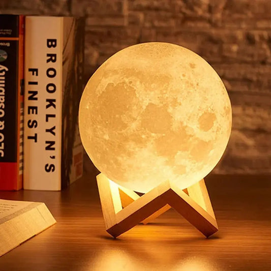 GLOBGRIP Book Light LED Moon Galaxy Night Light glowing on wooden stand next to books on a desk