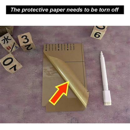 Protective paper being torn off from the writeable LED desk lamp surface with a white marker and wooden blocks nearby